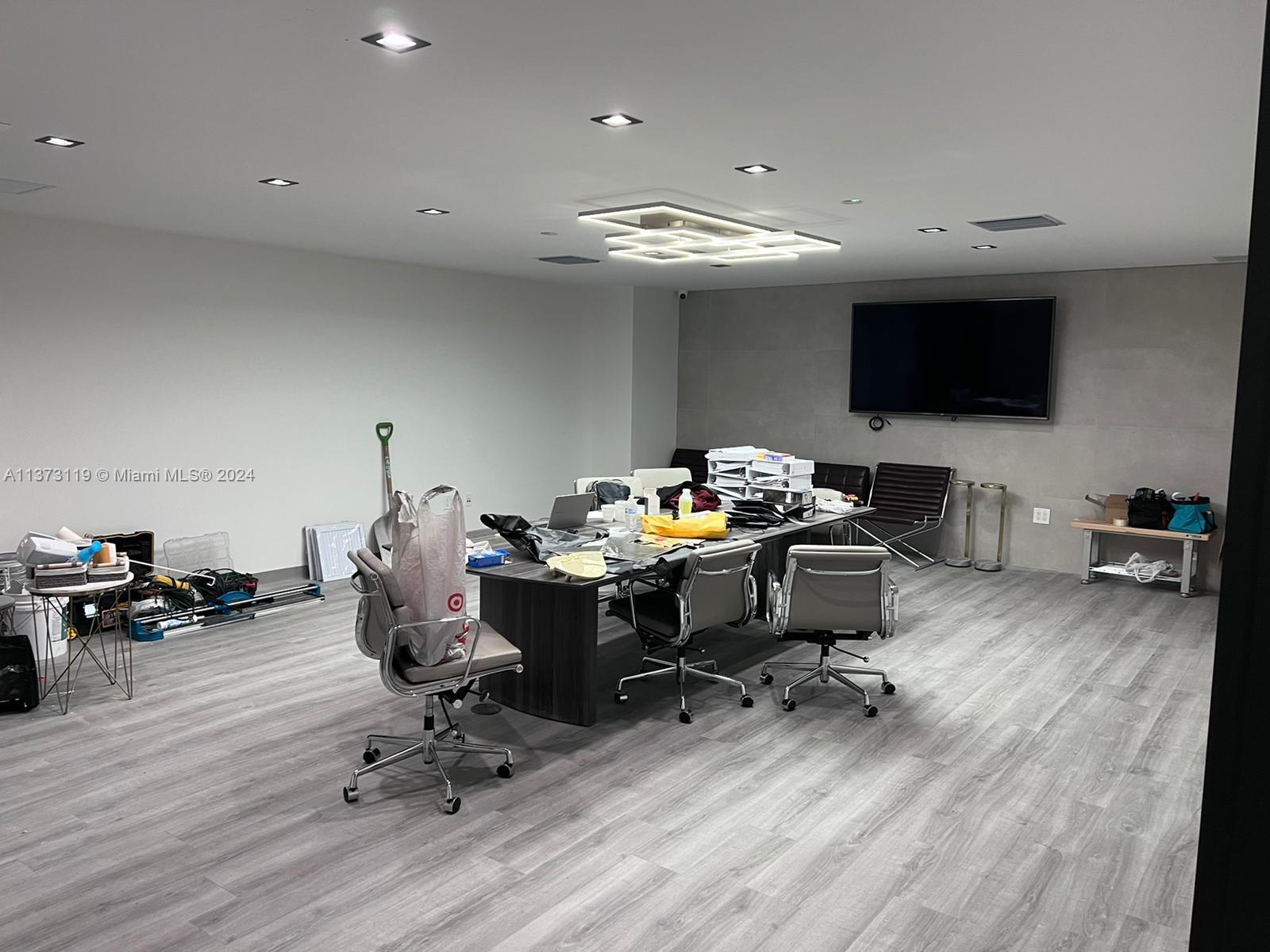 A modern office conference room features a large table, gray flooring, and a wall-mounted television — FORT LAUDERDALE, FL