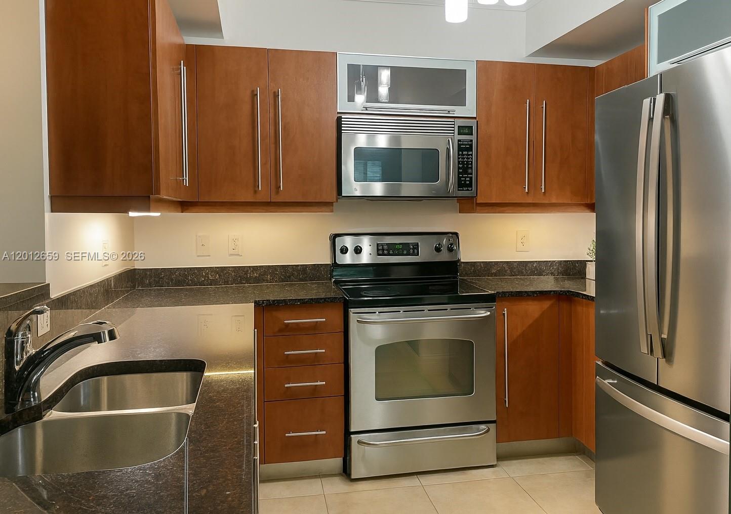 A kitchen features wood cabinets, stainless steel appliances, and dark granite countertops — 7355 SW 89th St # 501N, Miami FL 33156, MIAMI, FL