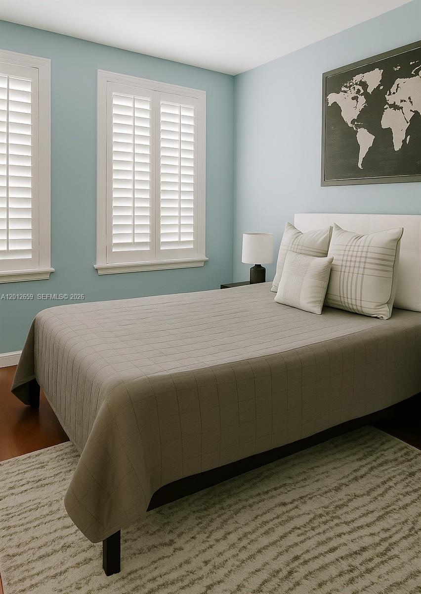 A bedroom features light blue walls, a bed with a grid-patterned quilt, and plantation shutters — 7355 SW 89th St # 501N, Miami FL 33156, MIAMI, FL