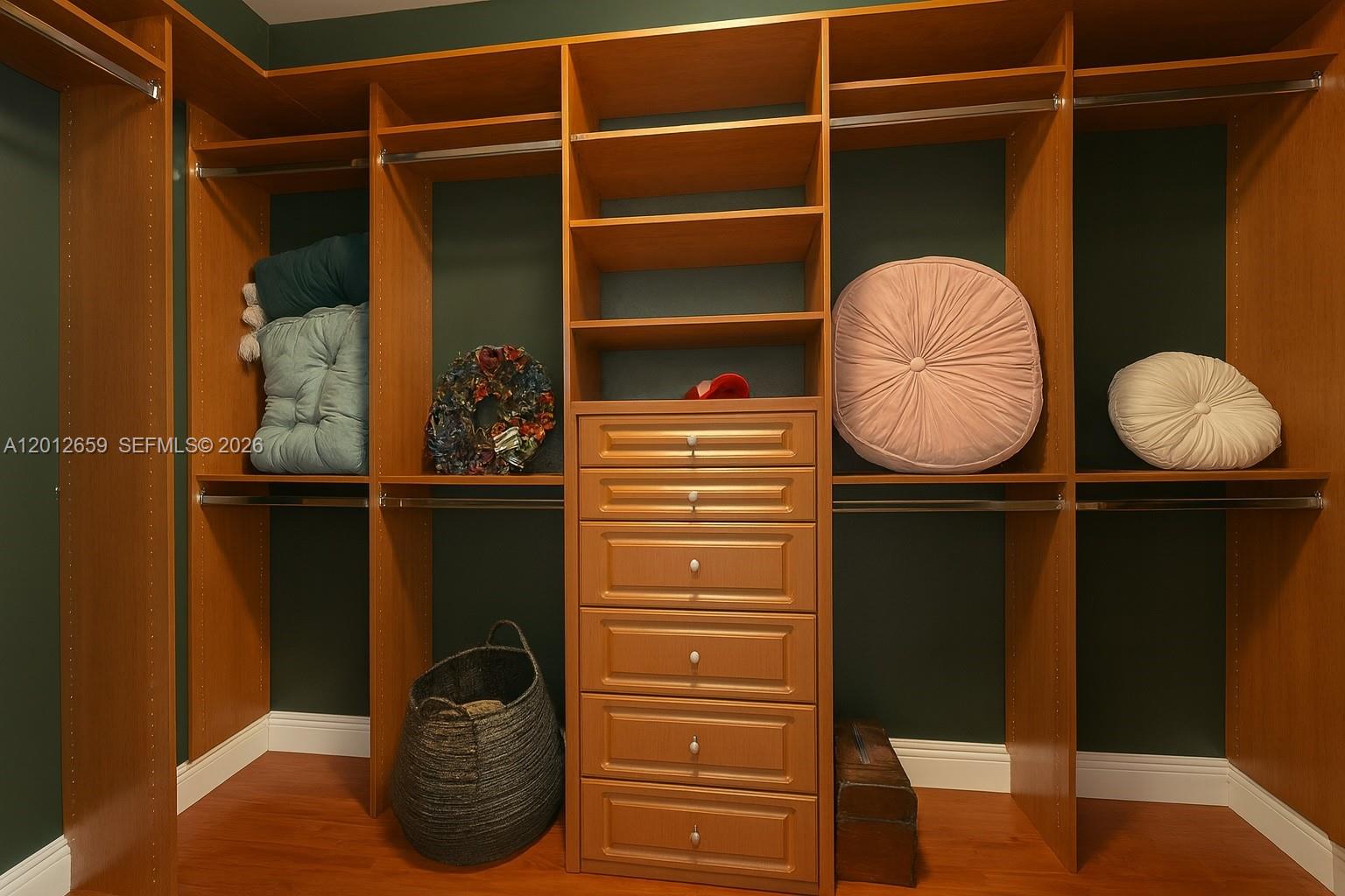 A walk-in closet features wooden shelving, a central drawer unit, and dark green walls — 7355 SW 89th St # 501N, Miami FL 33156, MIAMI, FL