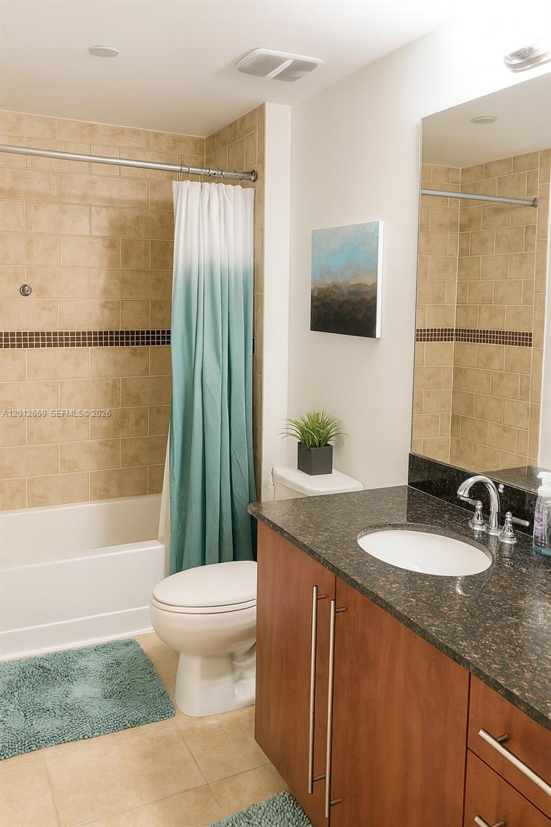 A bathroom features a tub-shower combo with tan tiles, a vanity, and a toilet — 7355 SW 89th St # 501N, Miami FL 33156, MIAMI, FL