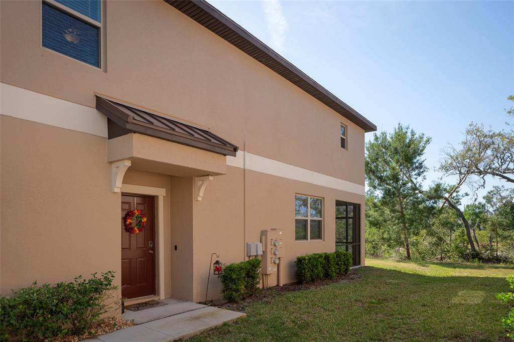 A tan two-story townhouse exterior with a brown front door and a metal awning — 11704 CASTINE STREET, NEW PORT RICHEY, FL