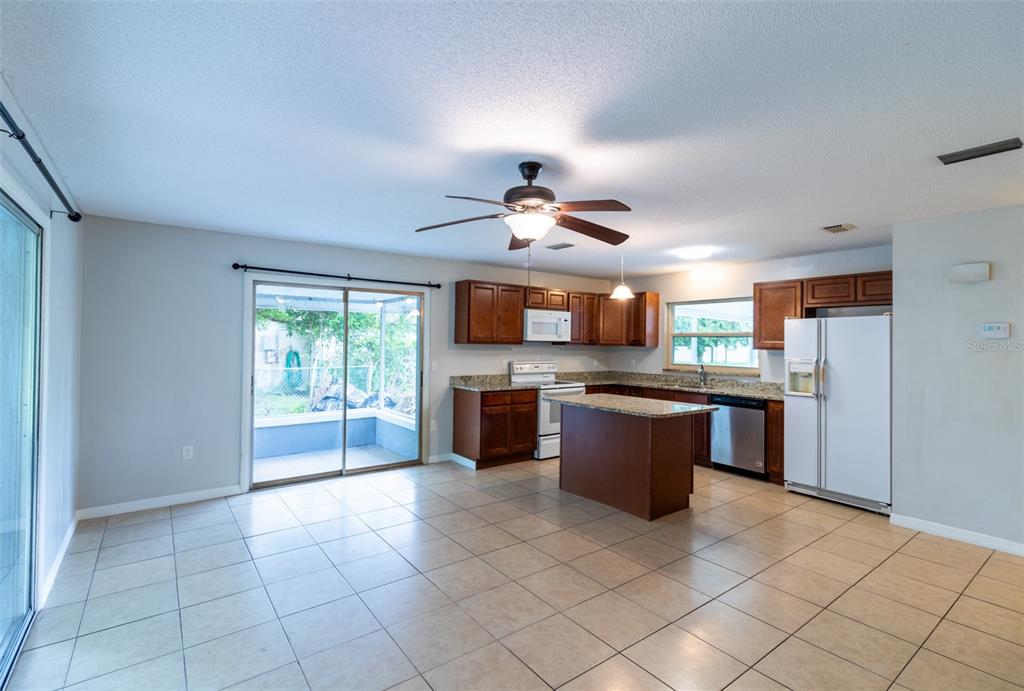 A kitchen with dark wood cabinets, granite countertops, an island, and tile flooring — 474 SPRING LANE, OCALA, FL
