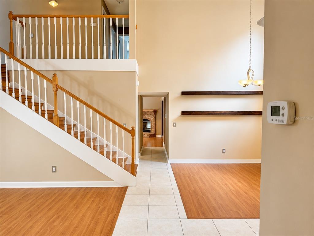 A two-story suburban house with tan siding, a brick facade, and a three-car garage — 1004 MUIRFIELD COURT, OVIEDO, FL