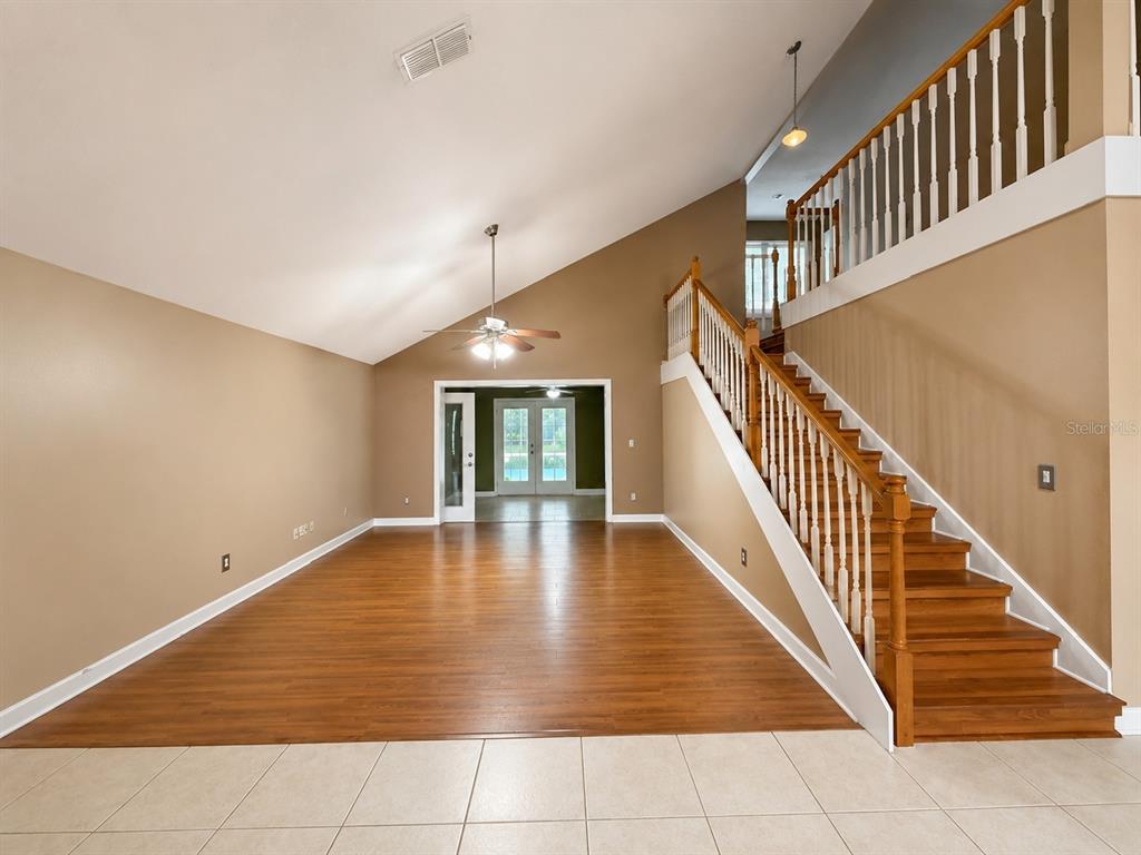 A foyer with tile flooring leads to a staircase and an adjacent room with wood floors — 1004 MUIRFIELD COURT, OVIEDO, FL