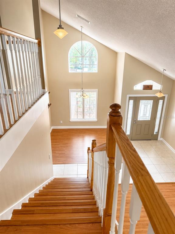 A living room with vaulted ceilings, wood flooring, and a staircase with a wooden railing — 1004 MUIRFIELD COURT, OVIEDO, FL