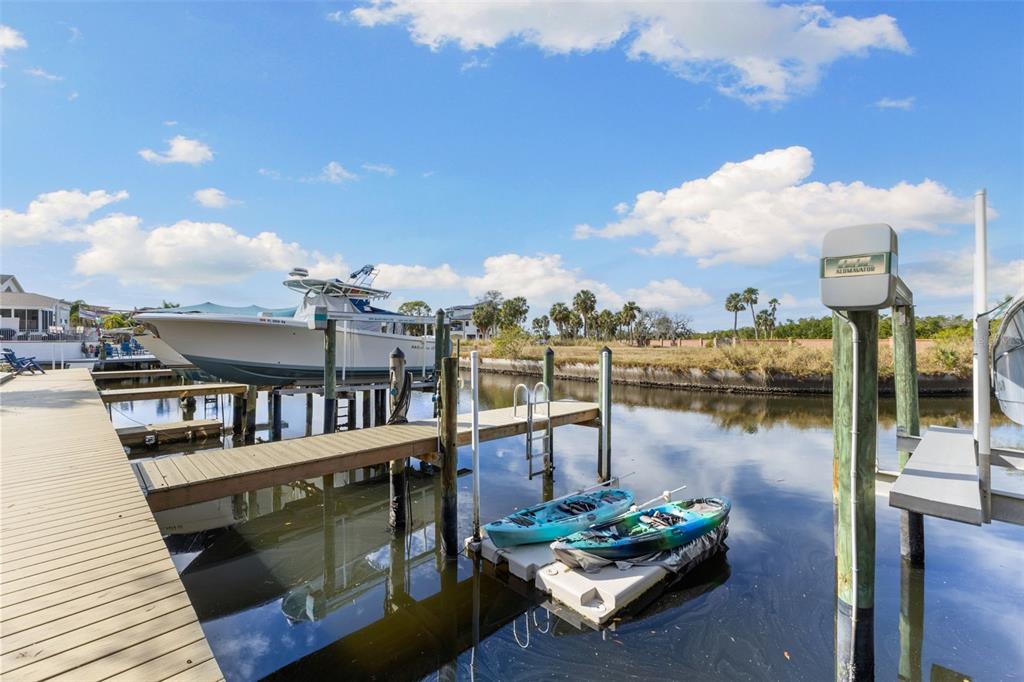 A wooden dock features a boat lift with a boat and two kayaks on a platform — 4533 HERON LODGE, NEW PORT RICHEY, FL