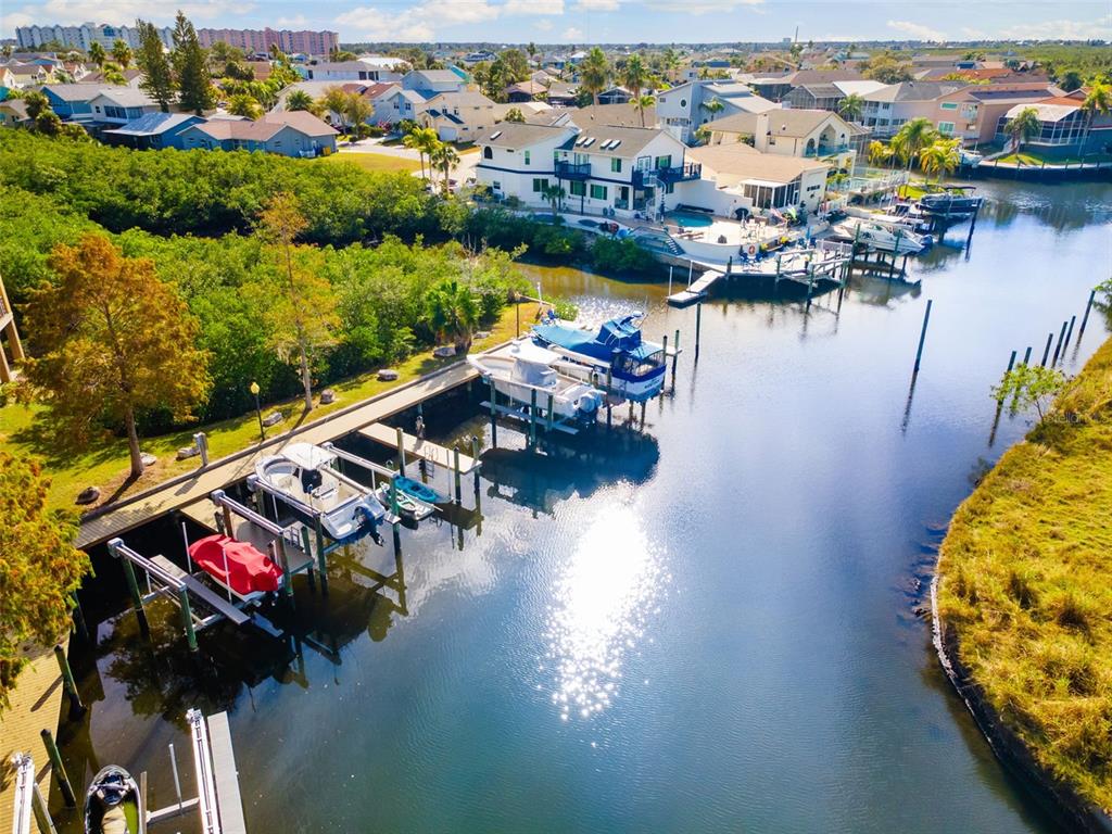 An aerial view shows a canal with multiple boats docked alongside a residential property — 4533 HERON LODGE, NEW PORT RICHEY, FL