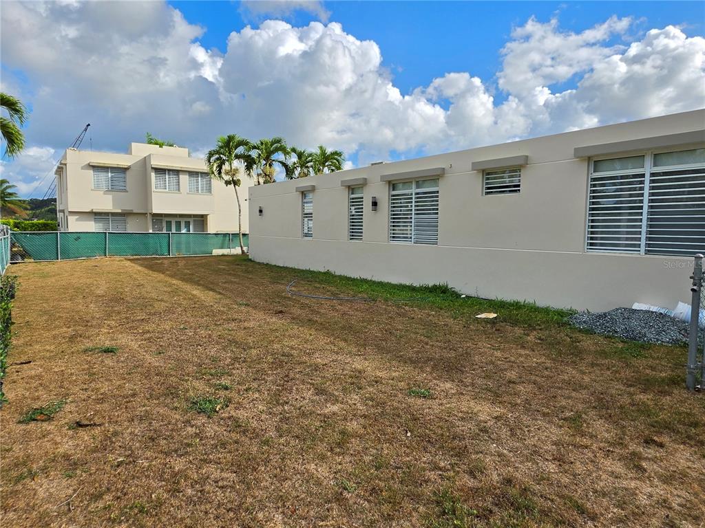A side view of a beige house with louvered windows and a dry grassy yard — 1 CALLE JARDIN, GURABO, PR