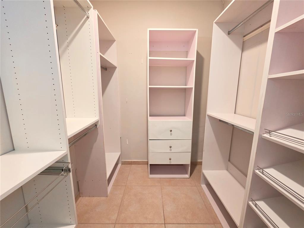 A walk-in closet features white modular shelving, hanging rods, and a central drawer unit — 1 CALLE JARDIN, GURABO, PR