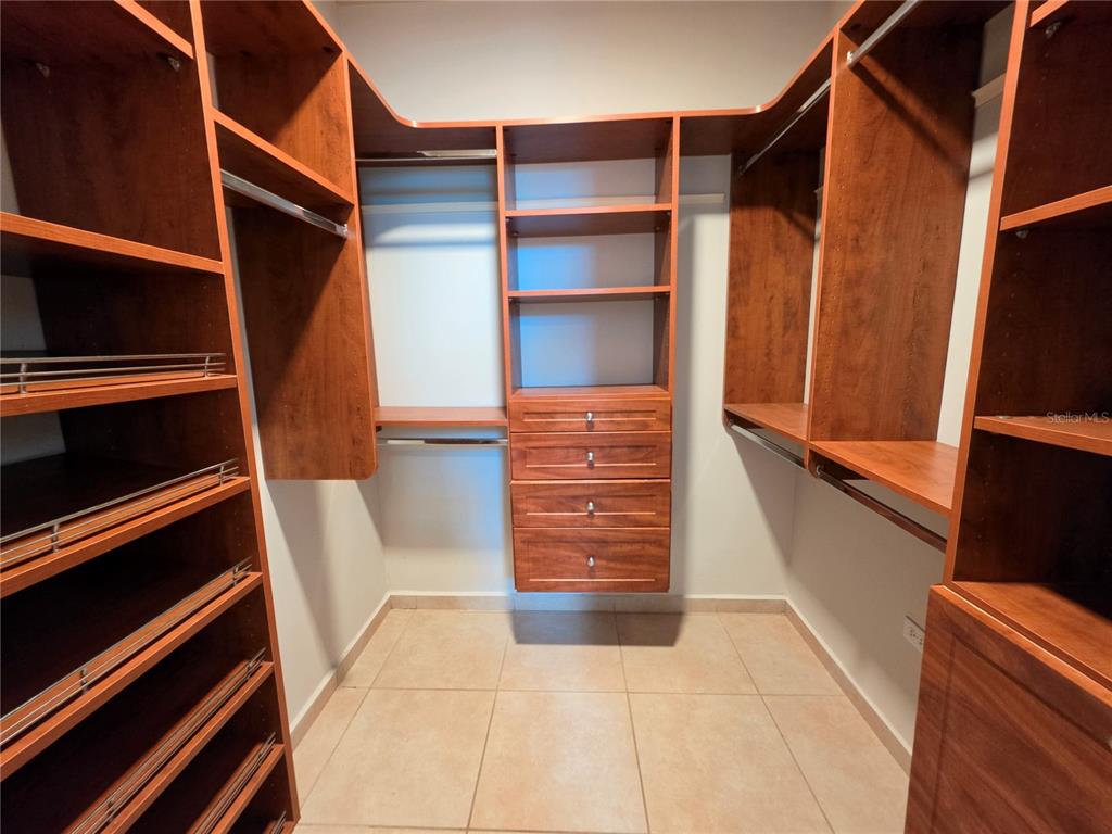 A walk-in closet features dark wood shelving, hanging rods, and a central stack of drawers — 1 CALLE JARDIN, GURABO, PR