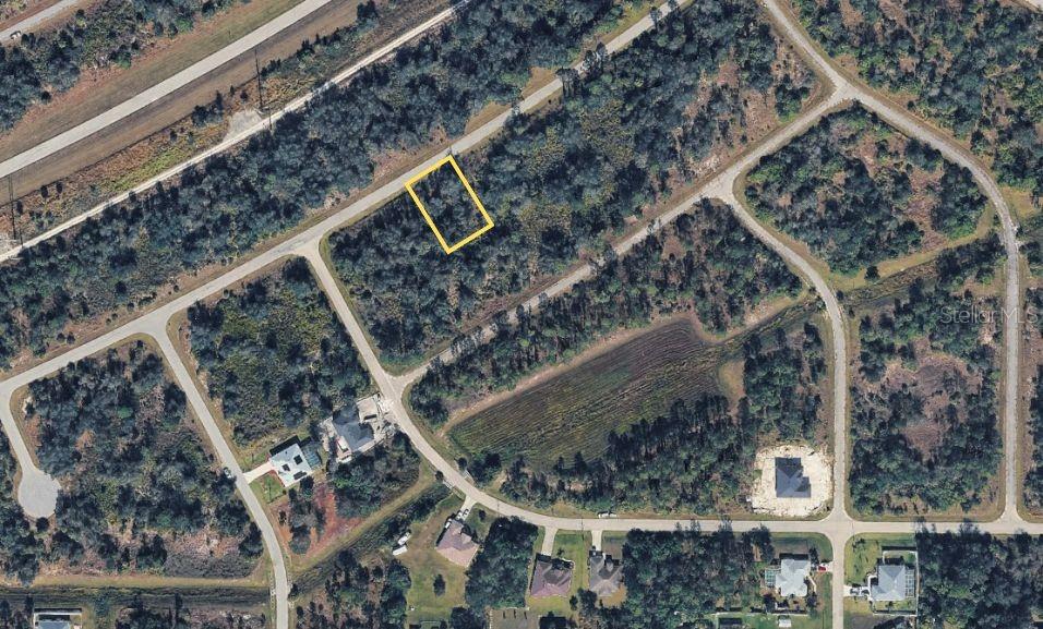 This aerial view shows a vacant, rectangular lot highlighted in yellow within a residential neighborhood — WYLAM DRIVE, NORTH PORT, FL