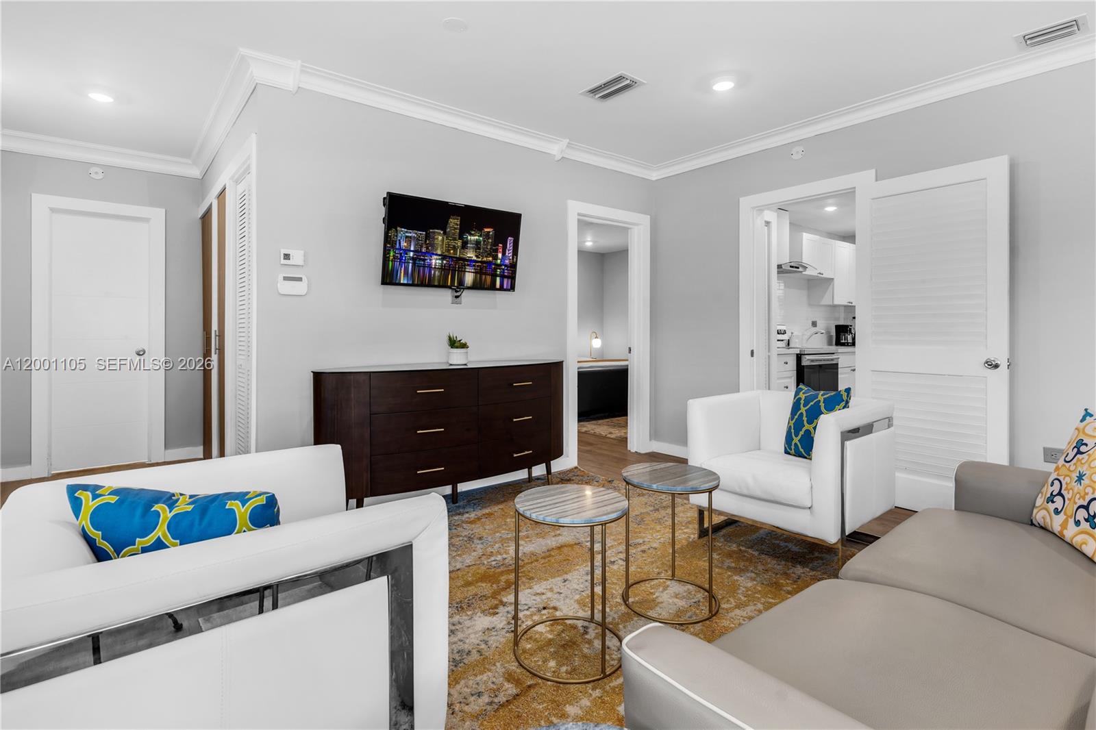 A living room features white armchairs, a gray sofa, a dark dresser, and two side tables — 8101 Harding Ave, Miami Beach FL 33141, MIAMI BEACH, FL