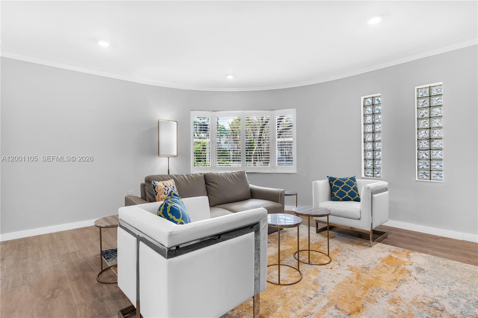 A living room features a curved wall, glass block windows, and modern furniture on flooring — 8101 Harding Ave, Miami Beach FL 33141, MIAMI BEACH, FL