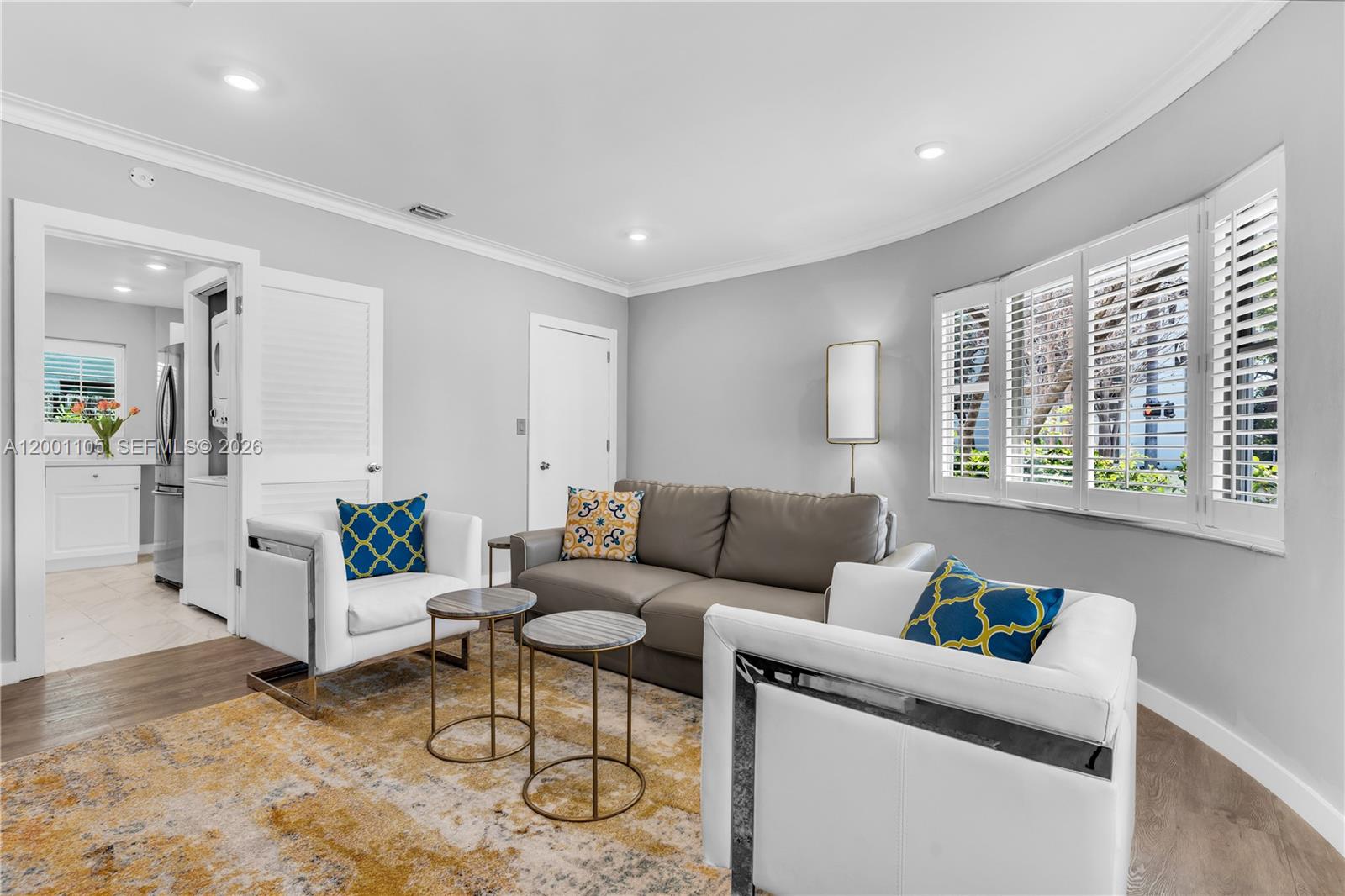 A living room features a grey sofa, two white armchairs, and two small round tables — 8101 Harding Ave, Miami Beach FL 33141, MIAMI BEACH, FL