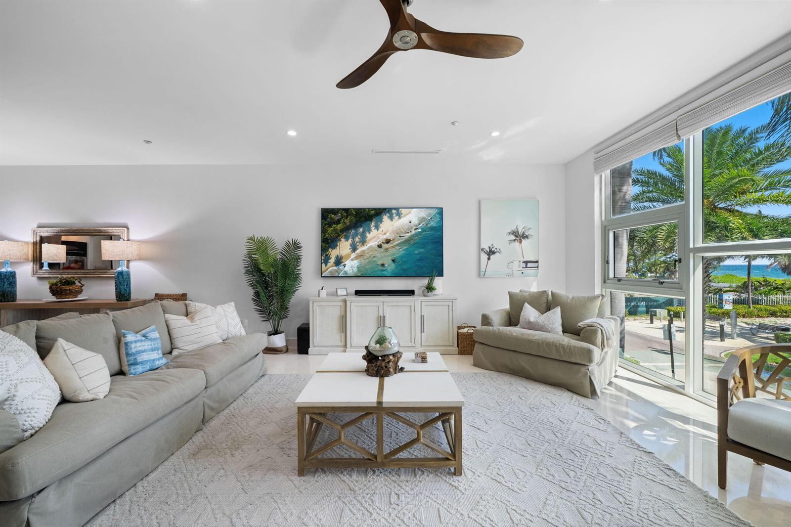 A bright living room features a large sectional sofa, a coffee table, and ocean views — 705 Briny Avenue, Pompano Beach FL 33062, POMPANO BEACH, FL