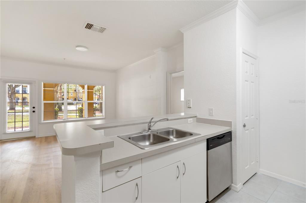 A kitchen with white cabinets, a stainless steel dishwasher, and a double-basin sink — 3599 CONROY ROAD UNIT 915, ORLANDO, FL