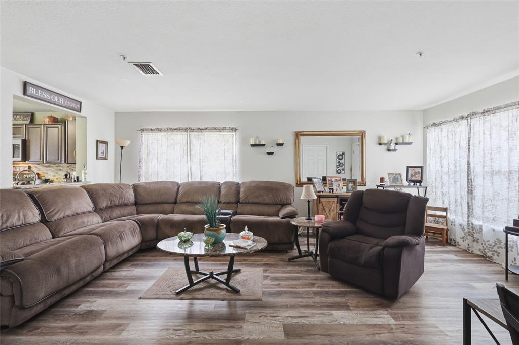 A living room features a large brown sectional, a recliner, and wood-look flooring — 3440 ALLSTON LANE, WINTER PARK, FL
