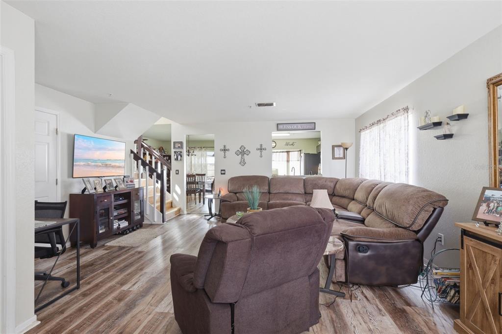 A living room features wood-look flooring, a large sectional sofa, a recliner, and a television — 3440 ALLSTON LANE, WINTER PARK, FL