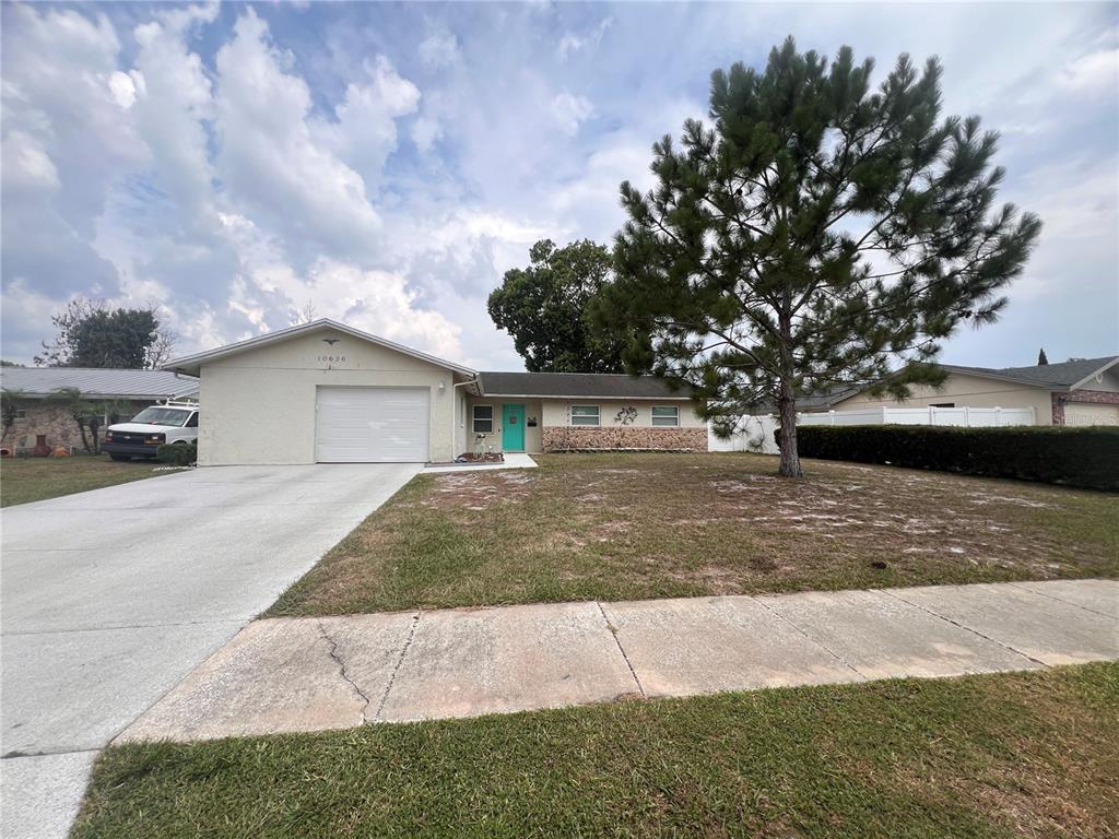 A single-story house with a white garage, turquoise front door, and a large pine tree — 10626 BRESSLYN BOULEVARD, ORLANDO, FL