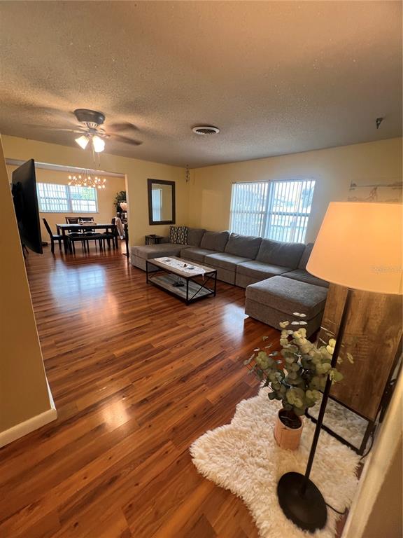 A living room with wood flooring, a large sectional sofa, and an adjacent dining area — 10626 BRESSLYN BOULEVARD, ORLANDO, FL