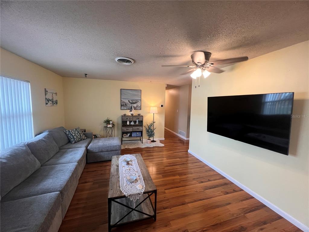 A living room features a gray sectional sofa, a wooden coffee table, and a wall-mounted television — 10626 BRESSLYN BOULEVARD, ORLANDO, FL