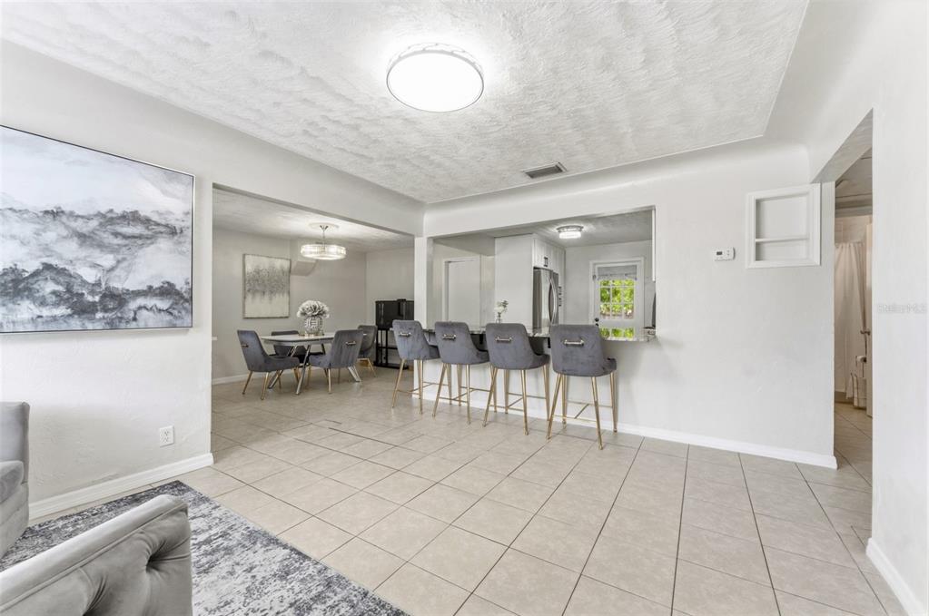 A living area with tile floors, a breakfast bar with four stools, and an adjacent dining room — 4610 71ST STREET N, ST PETERSBURG, FL