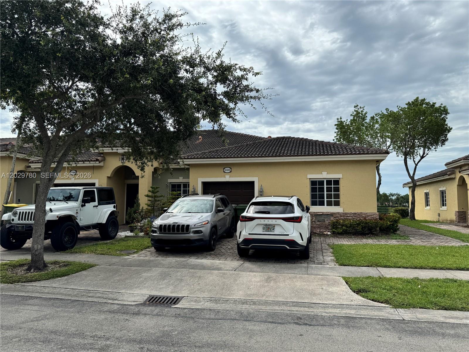 A single-story house with a tile roof, a two-car garage, and three parked vehicles — 3384 NE 11th Dr, Homestead FL 33033, HOMESTEAD, FL