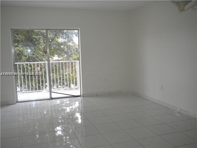 An empty room with white walls, white tile flooring, and a sliding glass door to a balcony — 260 NW 107th Ave # 207, Miami FL 33172, MIAMI, FL
