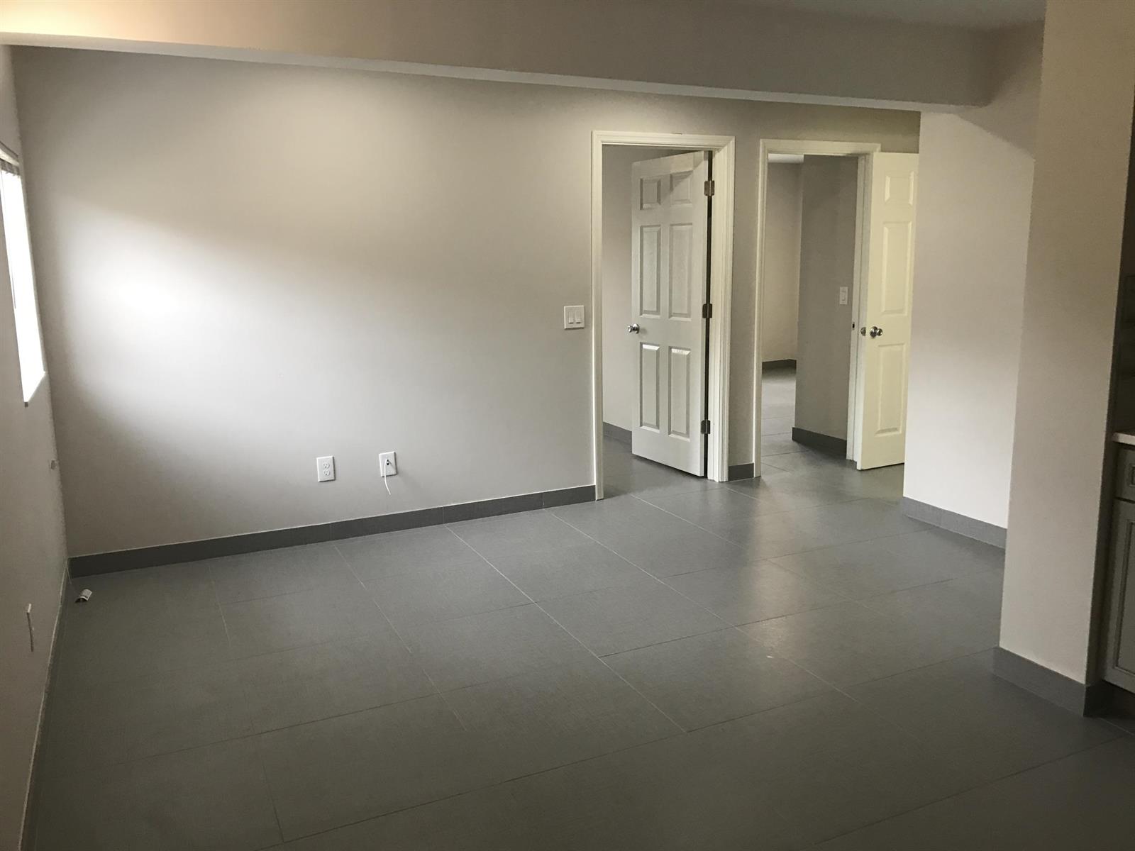 An empty room with gray tile flooring, white walls, and two open doorways — 142 SW 8th Avenue Apt D, Delray Beach FL 33444, DELRAY BEACH, FL