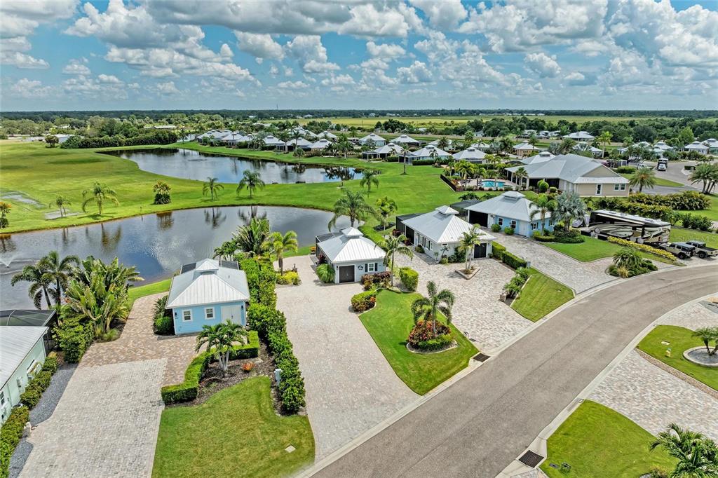 An aerial view shows several small, light blue houses with metal roofs near a pond — 8426 SW SAND CRANE CIRCLE LOT 81, ARCADIA, FL