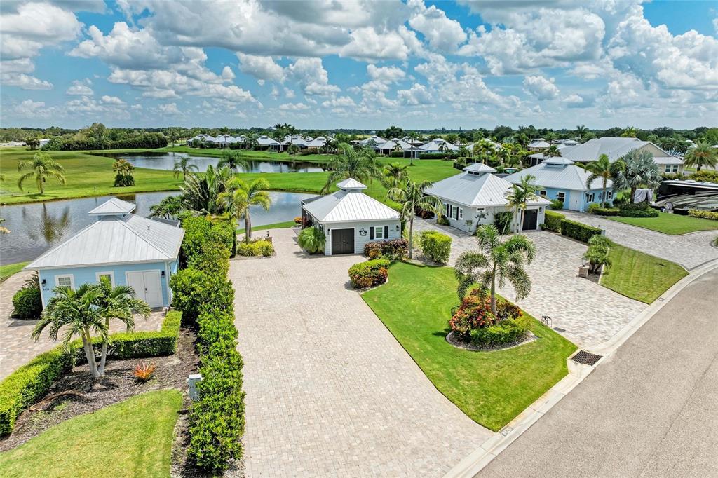 An aerial view shows three small houses with metal roofs and paved driveways near water — 8426 SW SAND CRANE CIRCLE LOT 81, ARCADIA, FL