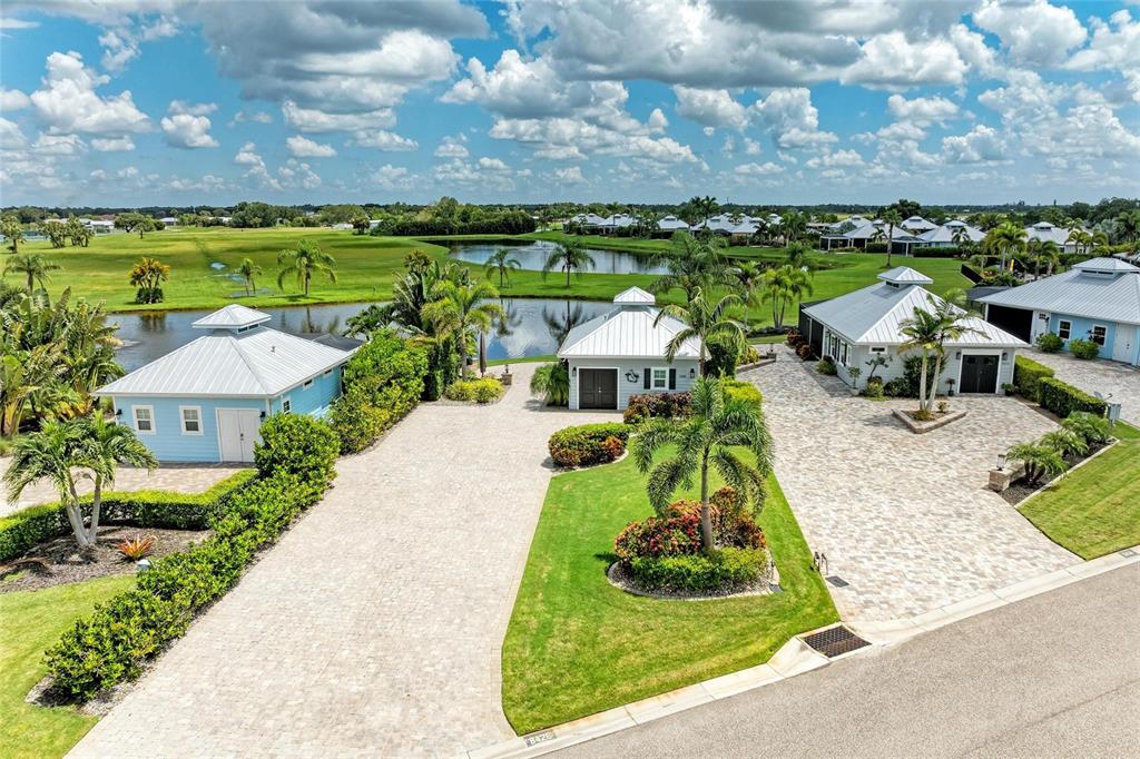 An aerial view shows three small houses with metal roofs and paved driveways near water — 8426 SW SAND CRANE CIRCLE LOT 81, ARCADIA, FL
