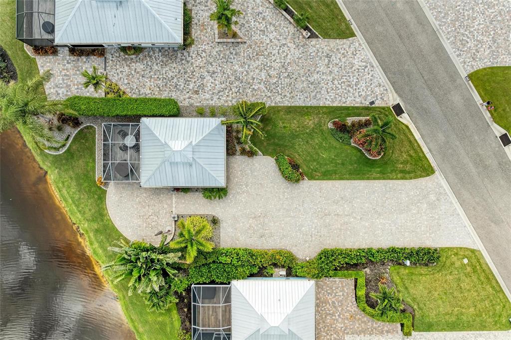 An aerial view shows two houses with metal roofs, paved driveways, and screened-in lanais — 8426 SW SAND CRANE CIRCLE LOT 81, ARCADIA, FL