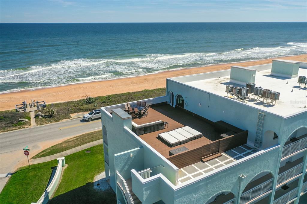An aerial view of a building rooftop deck featuring outdoor furniture overlooking the ocean — 3390 OCEAN SHORE BOULEVARD UNIT 402, ORMOND BEACH, FL