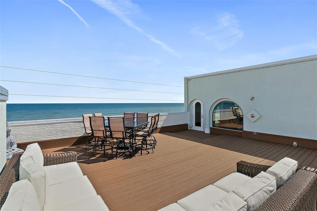 A rooftop deck features outdoor furniture, a dining set, and a view of the ocean — 3390 OCEAN SHORE BOULEVARD UNIT 402, ORMOND BEACH, FL