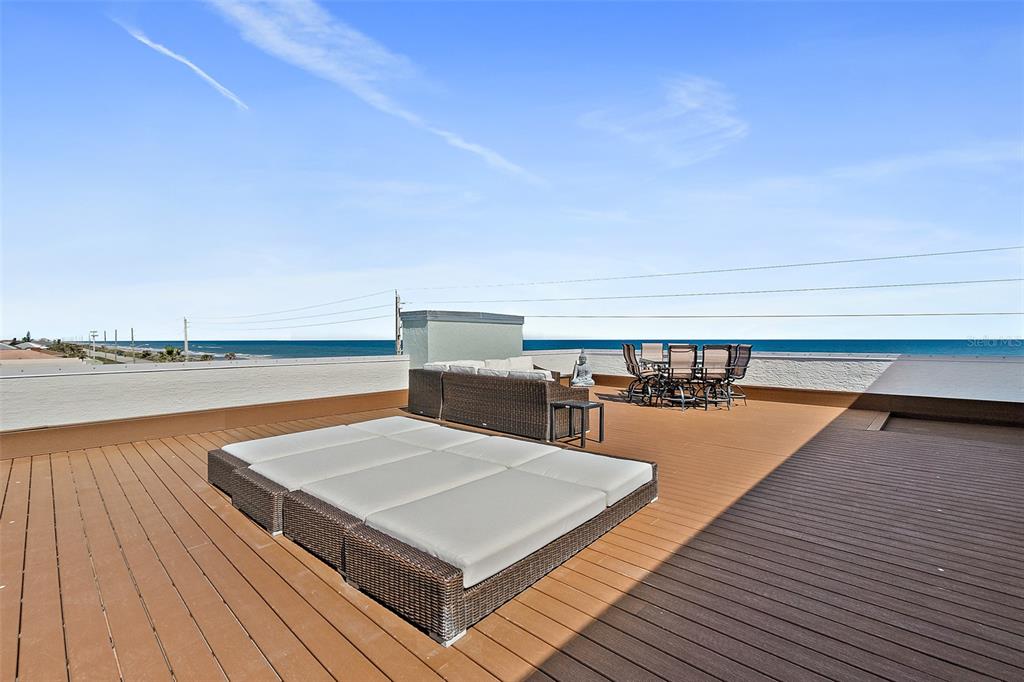 A rooftop deck features a large daybed, outdoor sofa, and dining set overlooking the ocean — 3390 OCEAN SHORE BOULEVARD UNIT 402, ORMOND BEACH, FL