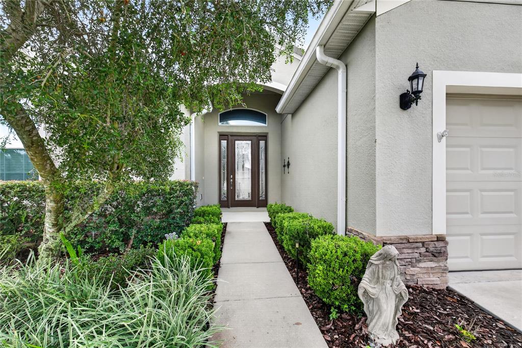 A concrete walkway leads to the front entrance of a house with a garage — 8356 BRIDGEPORT BAY CIRCLE, MOUNT DORA, FL