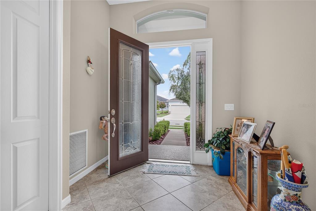 An entryway with tile flooring, a brown front door with glass inserts, and a transom window — 8356 BRIDGEPORT BAY CIRCLE, MOUNT DORA, FL