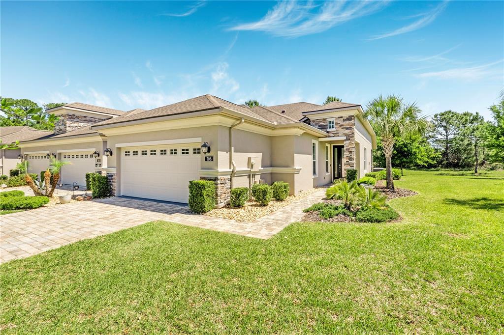 A single-story house with a beige stucco exterior, stone accents, and a two-car garage — 708 ALDENHAM LANE, ORMOND BEACH, FL