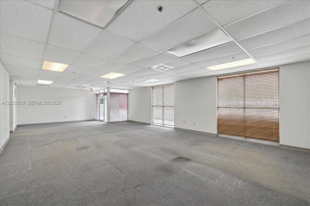 An empty office space features gray carpeting, a drop ceiling with recessed lighting, and large windows — 11077 NW 122nd St # 11, Medley FL 33178, MEDLEY, FL