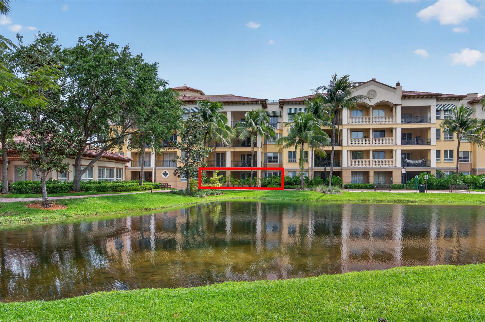 A multi-story apartment building with balconies overlooks a pond and landscaped lawn — 16135 Emerald Estates Drive # 164, Weston FL 33331, WESTON, FL