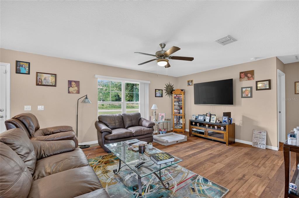 A living room features brown leather sofas, a glass coffee table, and a wall-mounted television — 38 JUNIPER LOOP COURT, OCALA, FL