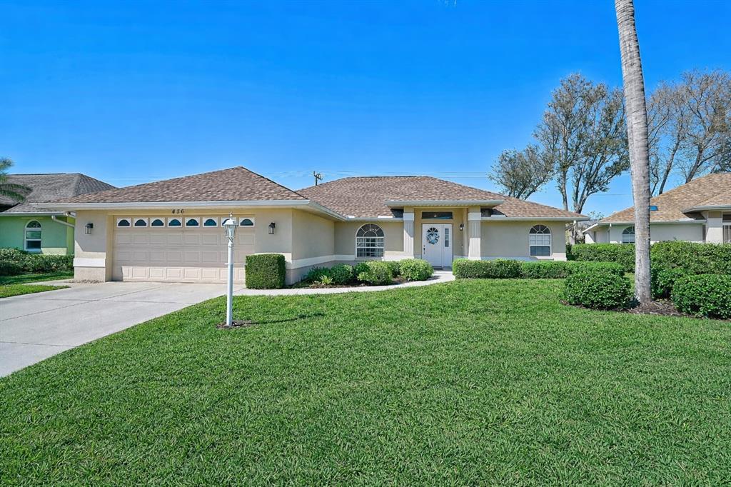 A single-story house with a tan stucco exterior, a two-car garage, and a manicured lawn — 426 BERMUDA ISLES CIRCLE, VENICE, FL