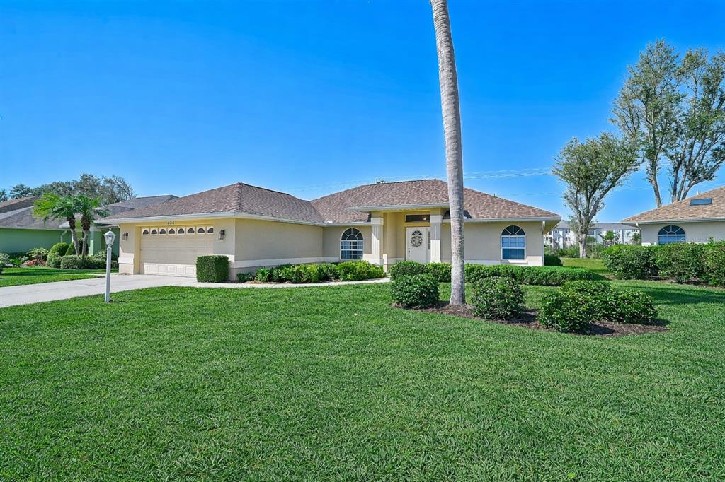 A single-story suburban house with a tan stucco exterior, a shingled roof, and a lawn — 426 BERMUDA ISLES CIRCLE, VENICE, FL