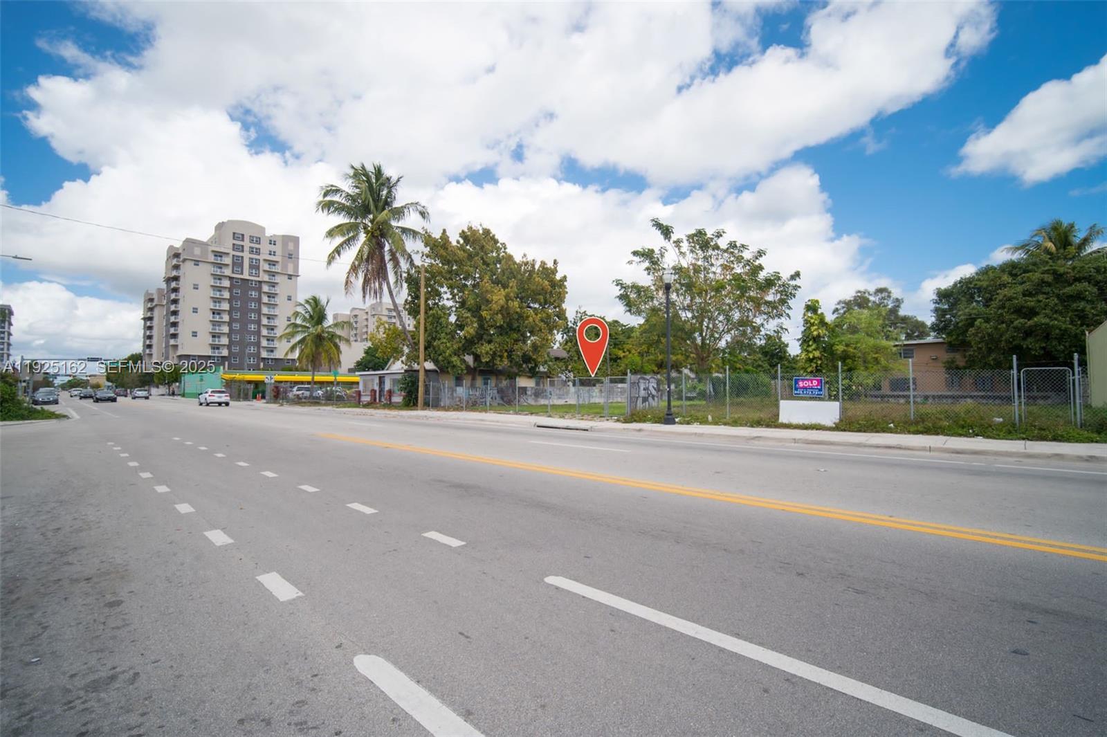 A vacant, fenced-in lot sits along a multi-lane road with a tall building nearby — 7635 NE 2nd Ave, Miami FL 33138, MIAMI, FL