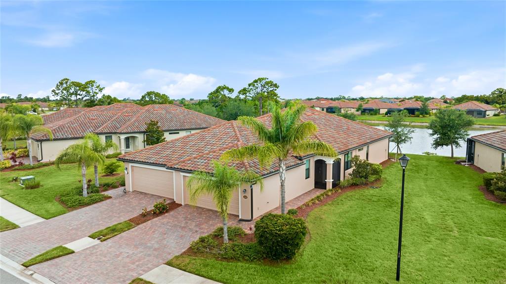 An aerial view shows a single-story house with a tile roof and a paved driveway — 12192 AMICA LOOP, VENICE, FL