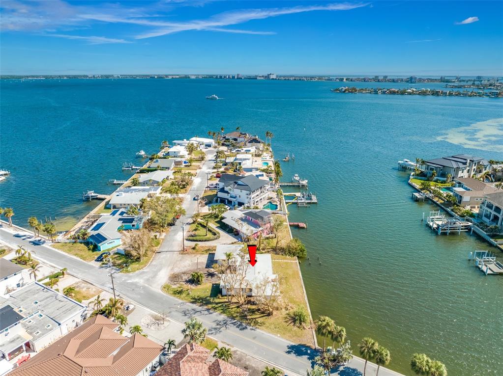 An aerial view shows a waterfront house on a peninsula with a red arrow pointing down — 5412 PALI WAY, ST PETE BEACH, FL