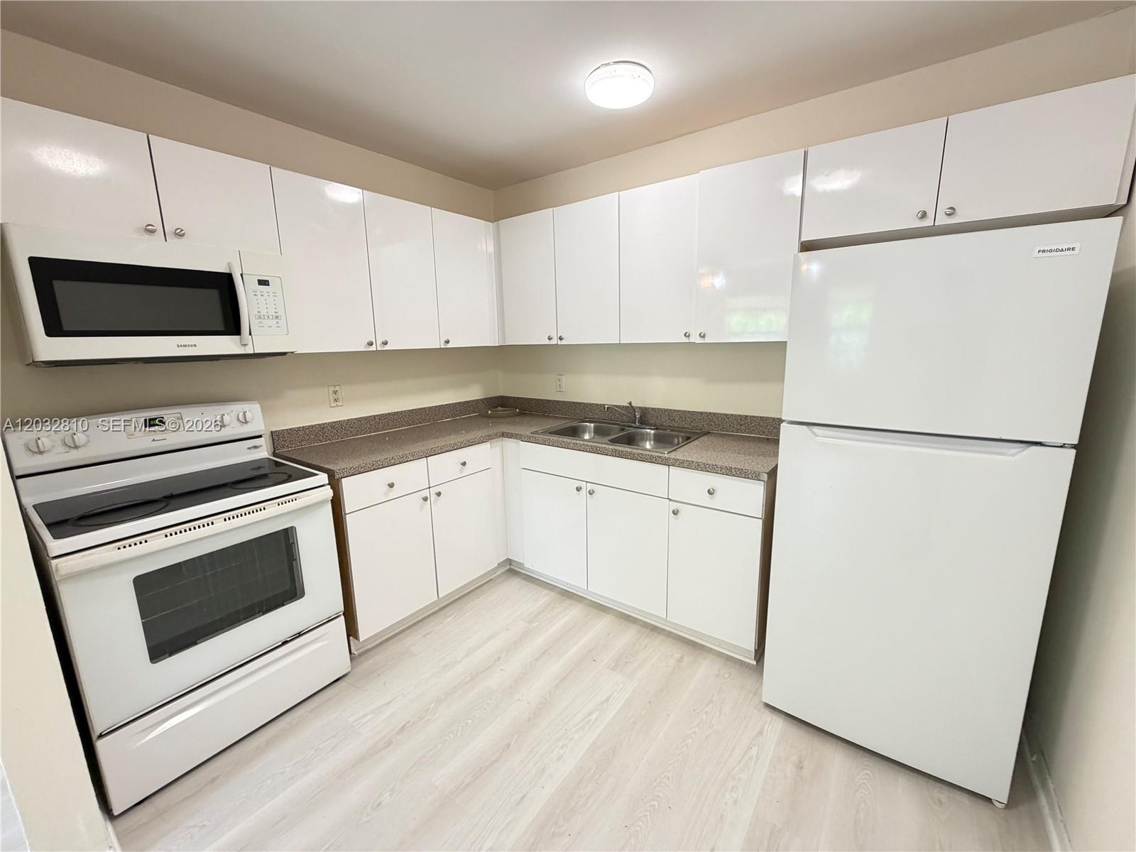 A kitchen features white cabinetry, a white stove, a white refrigerator, and light-colored flooring — 4801 SW 18th St # 2, West Park FL 33023, WEST PARK, FL