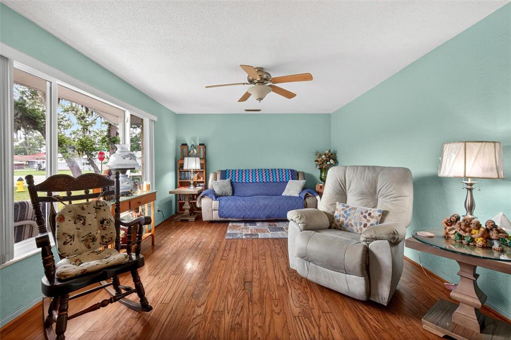 A living room features light blue walls, hardwood floors, a rocking chair, and a recliner — 201 POINCIANA AVENUE, PORT ORANGE, FL